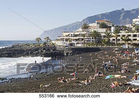 Stock Photograph - Tourists lying on beach, Playa De La Arena, Puerto De Santiago, Tenerife, Canary Islands, Spain . Fotosearch