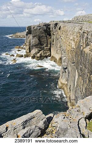 Stock Image - Tourists standing at coast, The Burren, County Clare, Munster, Ireland . Fotosearch