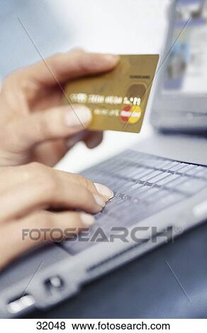 Stock Photo - Woman holding a credit card and using a laptop . Fotosearch