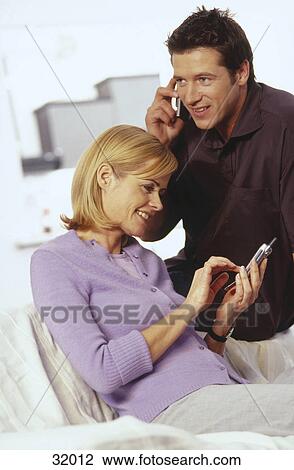 Stock Image - Young couple using mobile phones . Fotosearch