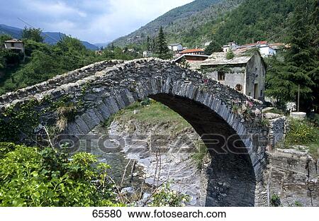 Stock Image - Arch bridge across river, Hinterland, Italy . Fotosearch