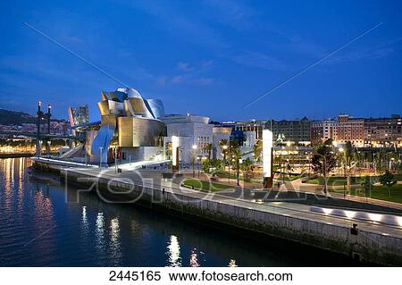 Stock Photography - Art museum lit up at dusk, Guggenheim Museum, Bilbao, Spain . Fotosearch