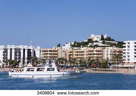 Picture - Boat with tourists at the beach of Santa Eularia des Riu, Ibiza, Spain, elevated view . Fotosearch