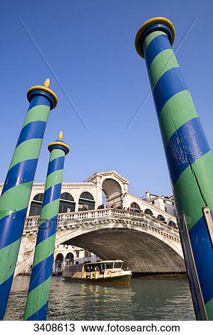 Boat with tourists under the Rialto Bridge, wooden pillars in the foreground, Venice, Italy, low angle view View Large Photo Image Stock Image - Boat with tourists under the Rialto Bridge, wooden pillars in the foreground, Venice, Italy, low angle view . Fotosearch