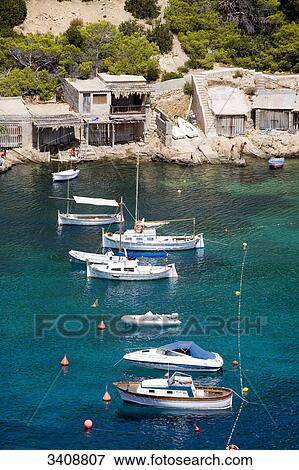 Stock Photo - Boats and boat houses at the bay of Cala Vadella, Ibiza, Spain, elevated view . Fotosearch