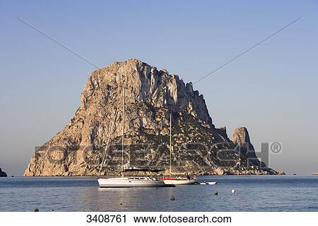 Stock Image - Boats in front of the rocky island Es Vedra, Cala d Hort, Ibiza, Spain . Fotosearch
