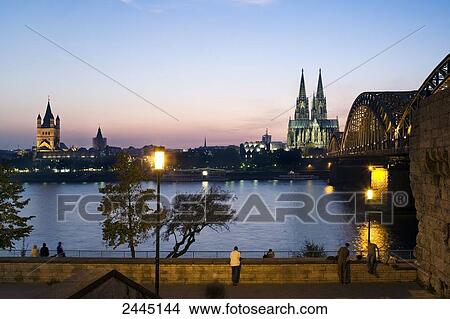 Picture - Bridge and church lit up at dusk, Hohenzollern Bridge, Cologne Cathedral, Cologne, Rhineland, North Rhine-Westphalia, Germany . Fotosearch