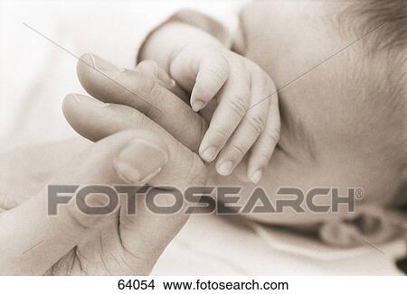 Close-up of a man's hand touching his baby's fingers View Large Photo Image Picture - Close-up of a man's hand touching his baby's fingers . Fotosearch