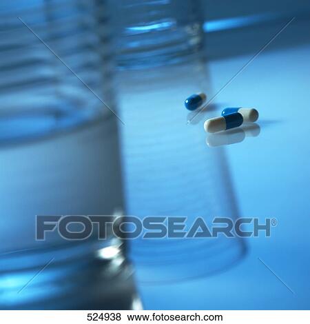 Stock Photo - Close-up of capsules and glass of water . Fotosearch