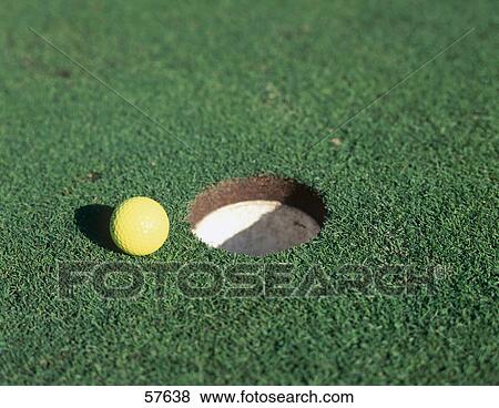 Stock Photo - Close-up of golf ball near hole on golf green . Fotosearch
