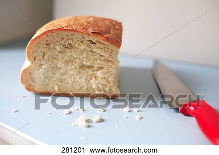 Stock Image - Close-up of piece of bread and knife on cutting board . Fotosearch