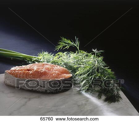 Stock Image - Close-up of slice of fish and dill on cutting board . Fotosearch