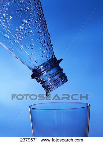 Stock Image - Close-up of water droplets being poured from bottle into glass . Fotosearch
