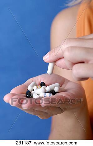 Stock Photo - Close-up of woman's hands holding pills and capsules . Fotosearch
