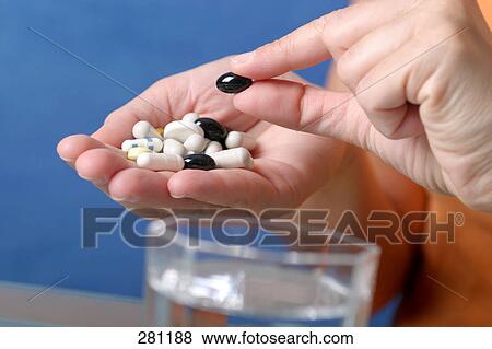 Stock Photo - Close-up of woman's hands holding pills and capsules . Fotosearch