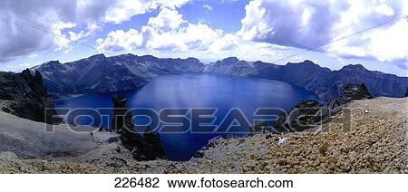 Stock Image - Clouds in sky above lake in valley, China . Fotosearch