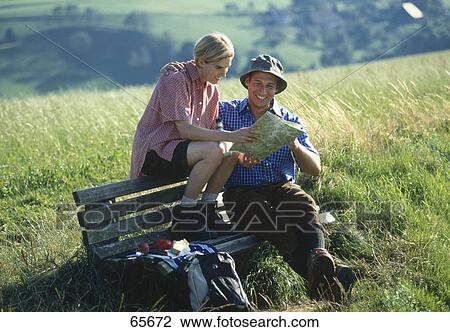 Stock Image - Couple reading map on bench, Germany . Fotosearch