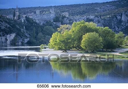 Stock Photograph - Deciduous trees at riverfront, Ardeche River, Pont-Saint-Esprit, France . Fotosearch