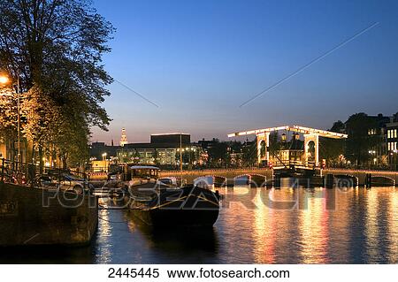 Drawbridge across river lit up at night, Magere Brug, Amstel River, Amsterdam, Netherlands View Large Photo Image Stock Photography - Drawbridge across river lit up at night, Magere Brug, Amstel River, Amsterdam, Netherlands . Fotosearch