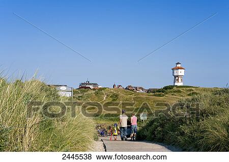 Family walking on boardwalk with lighthouse in background, Langeoog, Lower Saxony, Germany View Large Photo Image Stock Photo - Family walking on boardwalk with lighthouse in background, Langeoog, Lower Saxony, Germany . Fotosearch