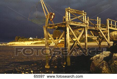 Stock Photo - Fishing net on wooden structure at coast, France Fishing net on wooden structure at coast, France . Fotosearch