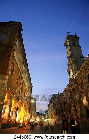 Stock Photo - Group of tourists in street lit up at dusk, Via Mercanti, Milan, Italy . Fotosearch