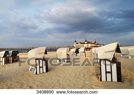 Stock Image - Hooded Beach Chairs on a sandy beach, Ahlbeck pier in the background, Usedom, Germany . Fotosearch