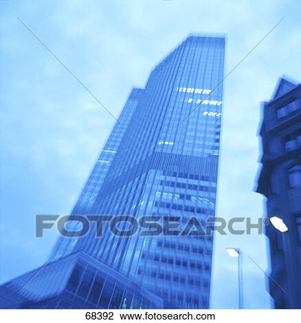 Stock Image - Low angle view of bank building lit up at dusk, Frankfurt, Hesse, Germany . Fotosearch
