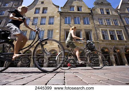 Low angle view of two women cycling in street, Prinzipialmarkt, Stadtturm, Muenster, North Rhine-Westphalia, Germany View Large Photo Image Stock Photo - Low angle view of two women cycling in street, Prinzipialmarkt, Stadtturm, Muenster, North Rhine-Westphalia, Germany . Fotosearch