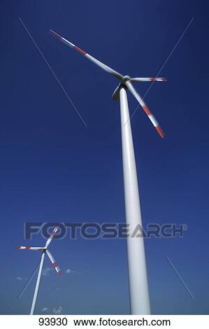 Low angle view of wind turbines against blue sky View Large Photo Image Stock Image - Low angle view of wind turbines against blue sky . Fotosearch