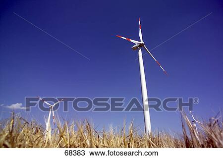 Stock Image - Low angle view of wind turbines in wheat field, Germany . Fotosearch