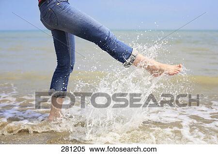 Stock Photography - Low section view of woman splashing water . Fotosearch