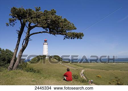 Man sitting in meadow with lighthouse in background, Dornbusch, Hiddensee Island, Mecklenburg-West Pomerania, Germany View Large Photo Image Picture - Man sitting in meadow with lighthouse in background, Dornbusch, Hiddensee Island, Mecklenburg-West Pomerania, Germany . Fotosearch