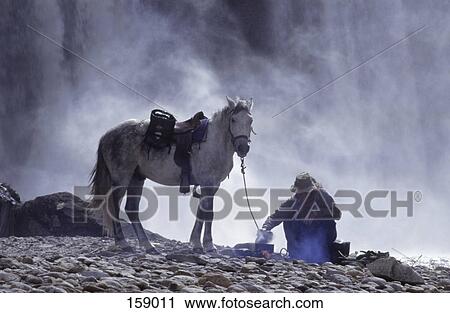 Stock Image - Man with horse near campfire on landscape, Mexico . Fotosearch