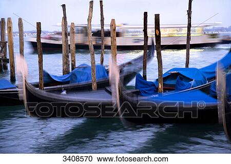 Moored gondolas, boat driving in the background, Venice, Italy View Large Photo Image Stock Image - Moored gondolas, boat driving in the background, Venice, Italy . Fotosearch