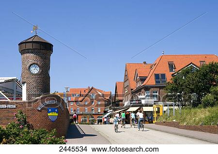 Picture - People cycling in street near clock tower, Juist, Lower Saxony, Germany . Fotosearch
