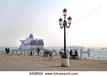 People on a seaside promenade in Venice, ferry in the background, Italy View Large Photo Image Stock Photo - People on a seaside promenade in Venice, ferry in the background, Italy . Fotosearch