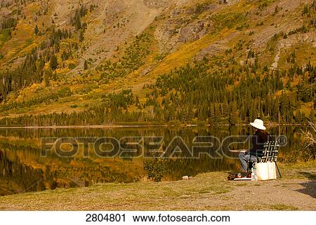 Person sitting at lakeside, Glacier National Park, Montana, USA View Large Photo Image Stock Image - Person sitting at lakeside, Glacier National Park, Montana, USA . Fotosearch