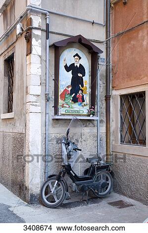 Picture - Picture of a saint and moped at house facade, Chioggia, Venetia, Italy . Fotosearch