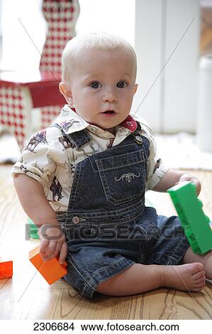 Picture - Portrait of baby boy playing with toys on wooden floor . Fotosearch