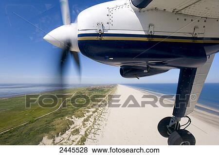 Stock Photo - Propeller plane flying over beach . Fotosearch
