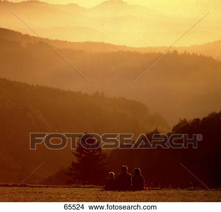 Picture - Rear view of family sitting on mountain in foggy weather . Fotosearch