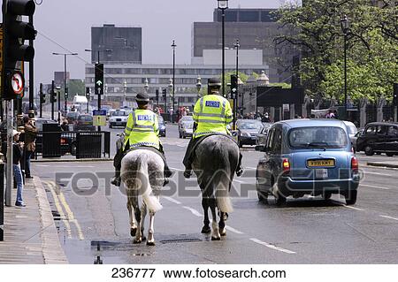Rear view of two policemen riding horses on road View Large Photo Image Stock Photo - Rear view of two policemen riding horses on road . Fotosearch