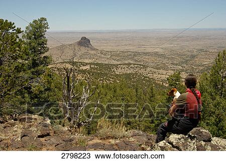 Rear view of woman sitting with dog on mountain, New Mexico, USA View Large Photo Image Stock Image - Rear view of woman sitting with dog on mountain, New Mexico, USA . Fotosearch