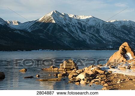 Stock Photo - River flowing in front of snowcapped mountains, Colorado, USA . Fotosearch