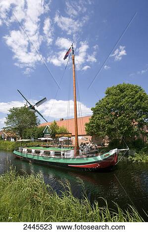 Sailboat in canal with industrial windmill in background, Ostgrossefehn, Lower Saxony, Germany View Large Photo Image Stock Image - Sailboat in canal with industrial windmill in background, Ostgrossefehn, Lower Saxony, Germany . Fotosearch