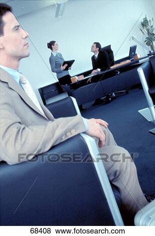 Side profile of businessman sitting in armchair with two businesspeople in background View Large Photo Image Stock Photo - Side profile of businessman sitting in armchair with two businesspeople in background . Fotosearch
