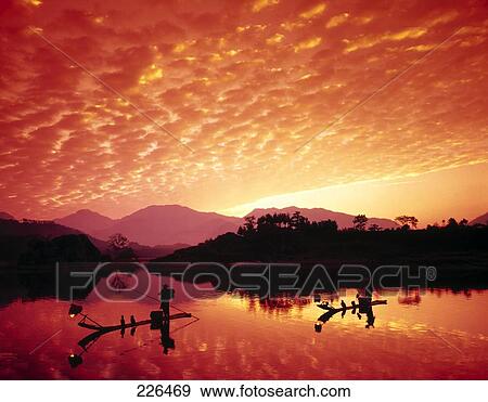 Stock Photo - Silhouette of two boatmen on boats at dusk, China . Fotosearch