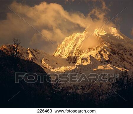 Snowcovered mountain peak surrounded by clouds, China View Large Photo Image Stock Image - Snowcovered mountain peak surrounded by clouds, China . Fotosearch