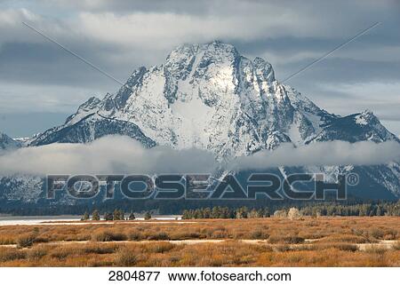 Stock Photo - Storm clouds over snowcapped mountain, Grand Teton, Grand Teton National Park, Wyoming, USA . Fotosearch